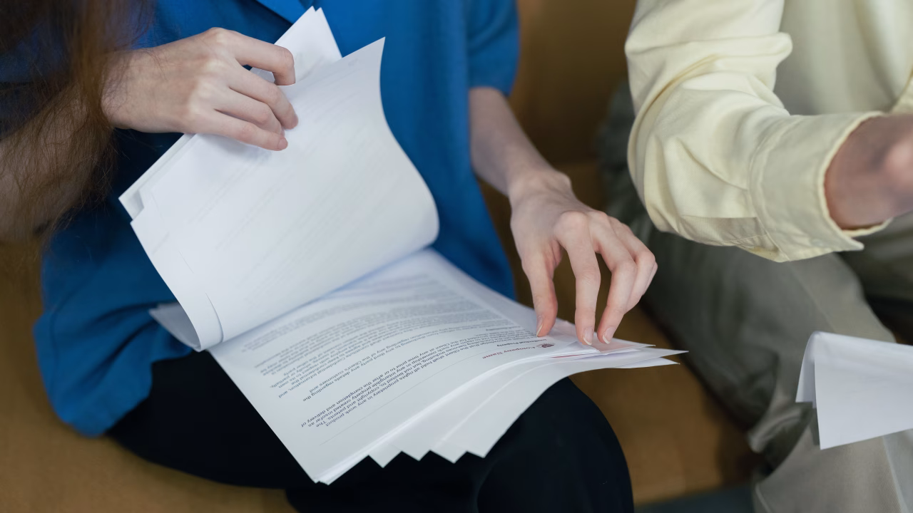 Unopened mortgage letters and a calendar on a kitchen table beside a cup of coffee.